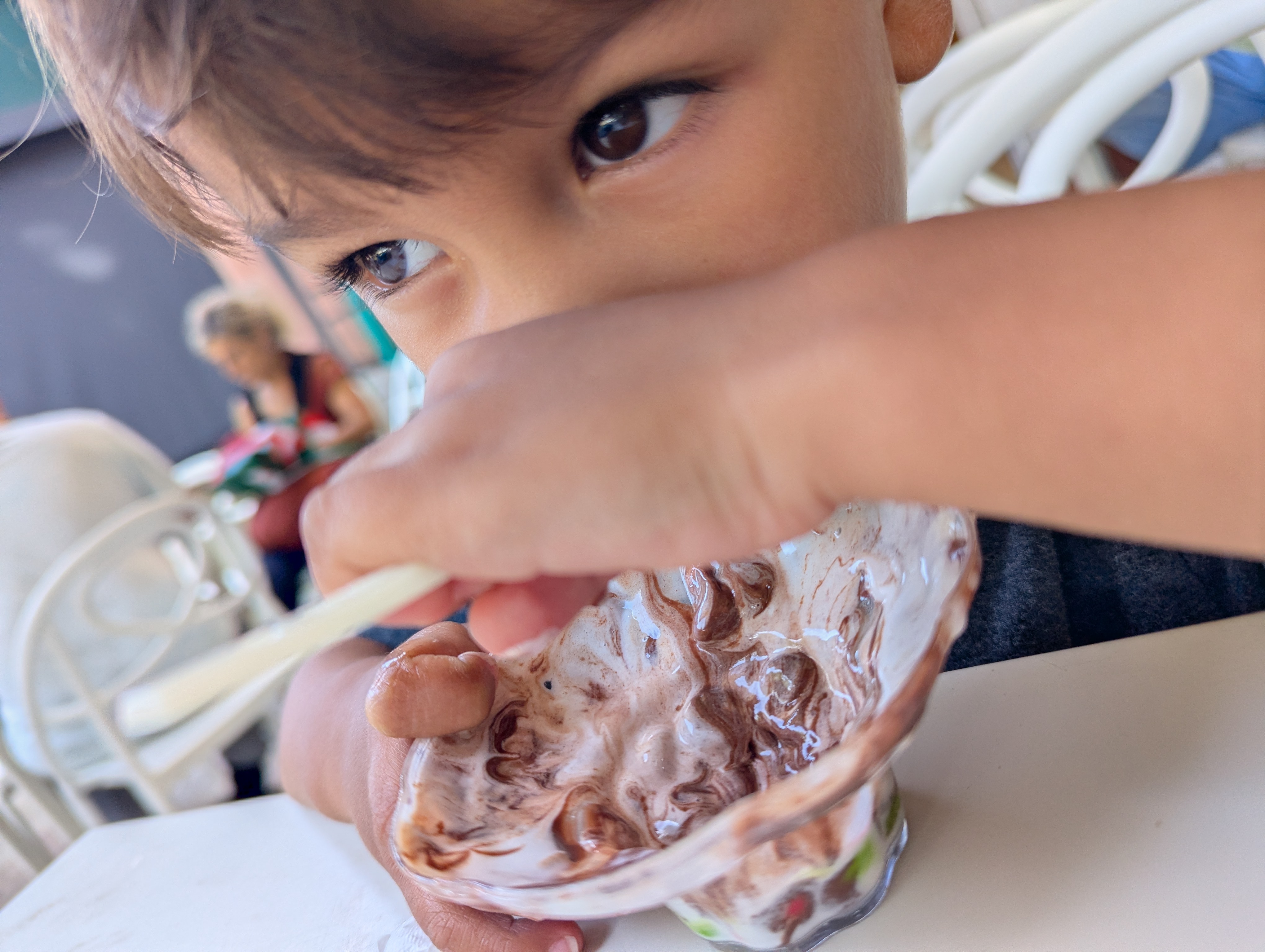 Arlo's face right up close to an almost-finished gelato cup, eyes focused, spoon in hand