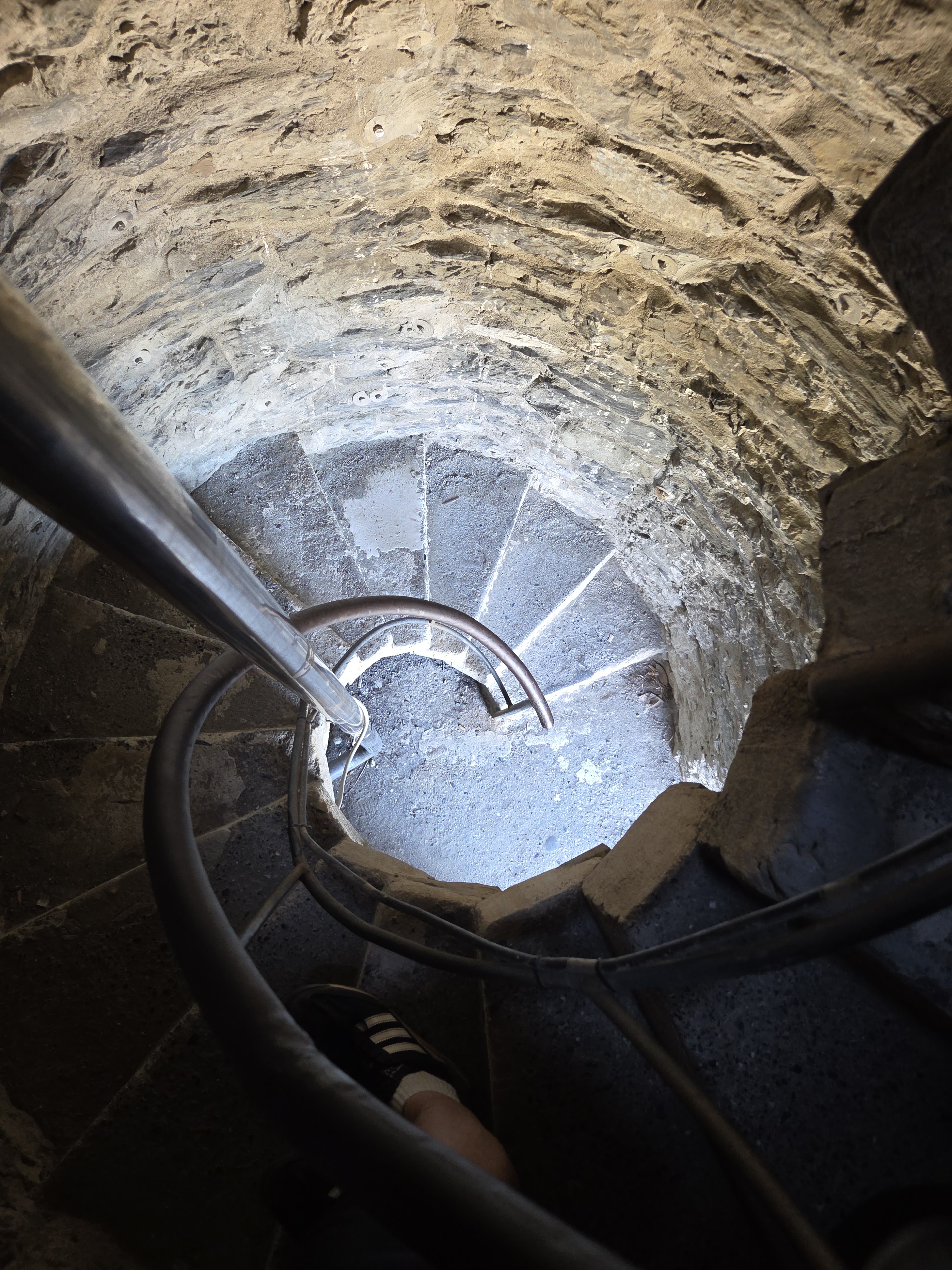 Looking down a narrow stone spiral staircase inside the tower of Castello Doria