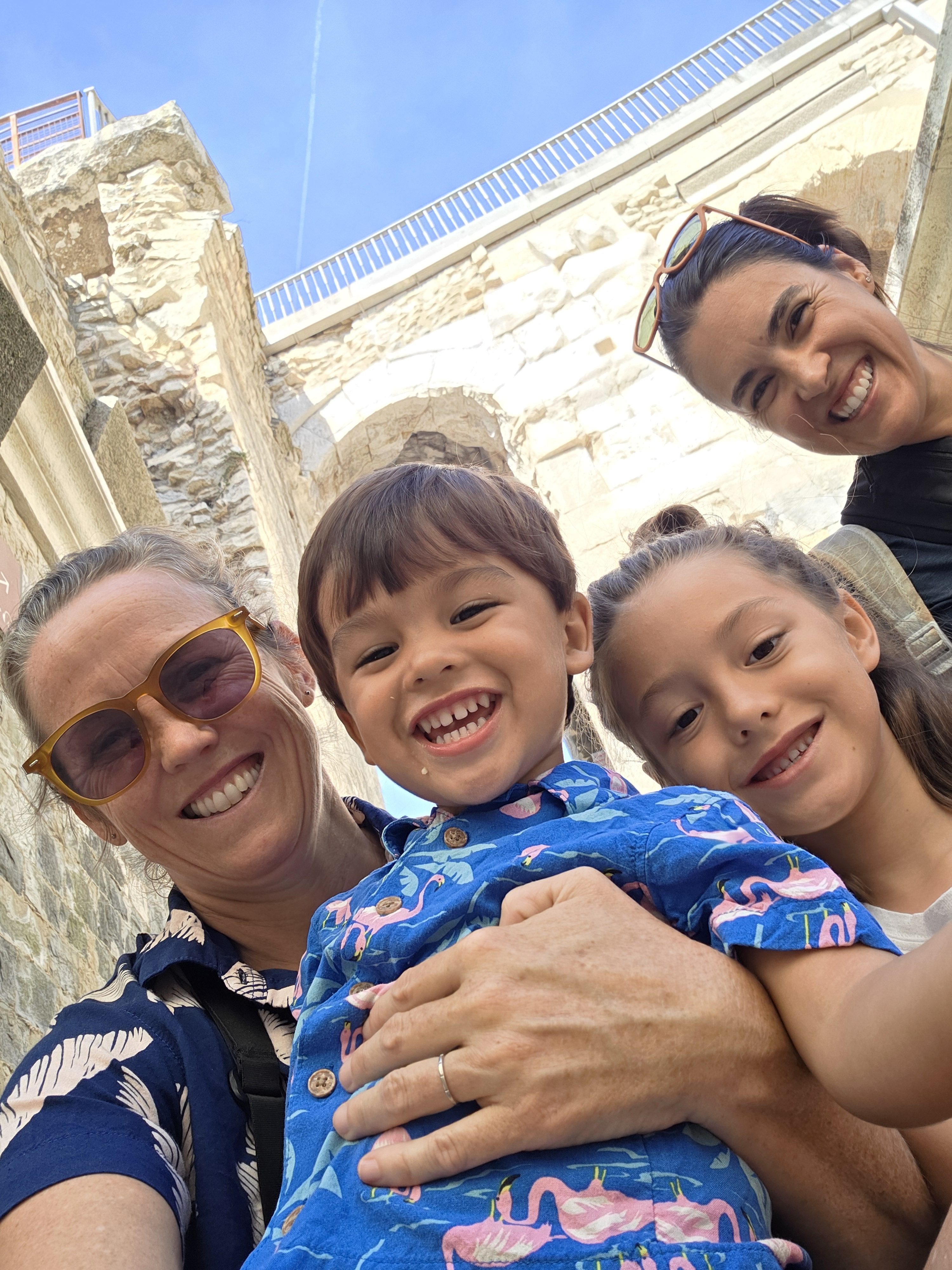 The whole family grinning in a selfie taken from below inside the arena's stone corridors, arches and stonework above