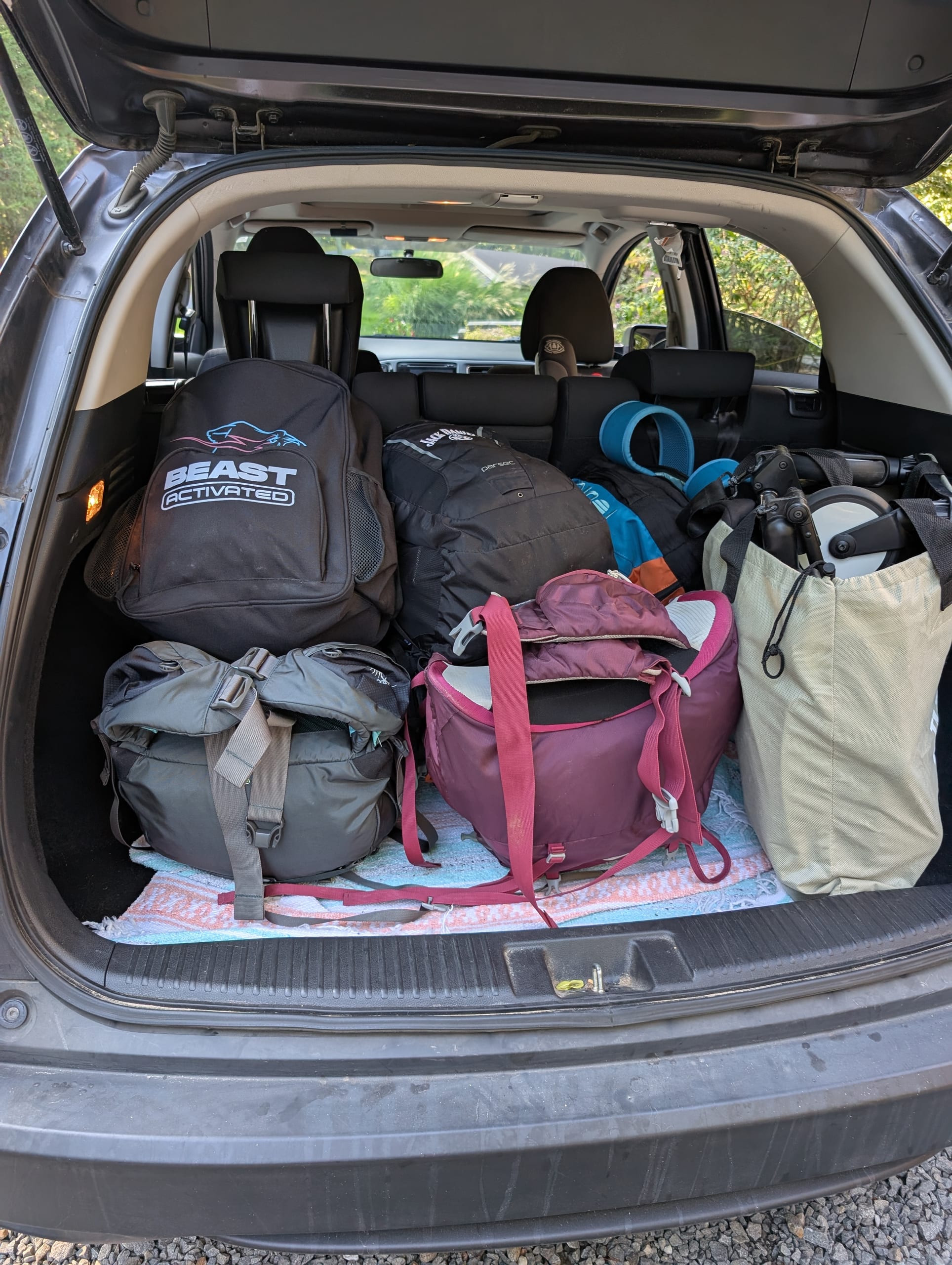 A car trunk packed with backpacks and gear for a family backpacking trip