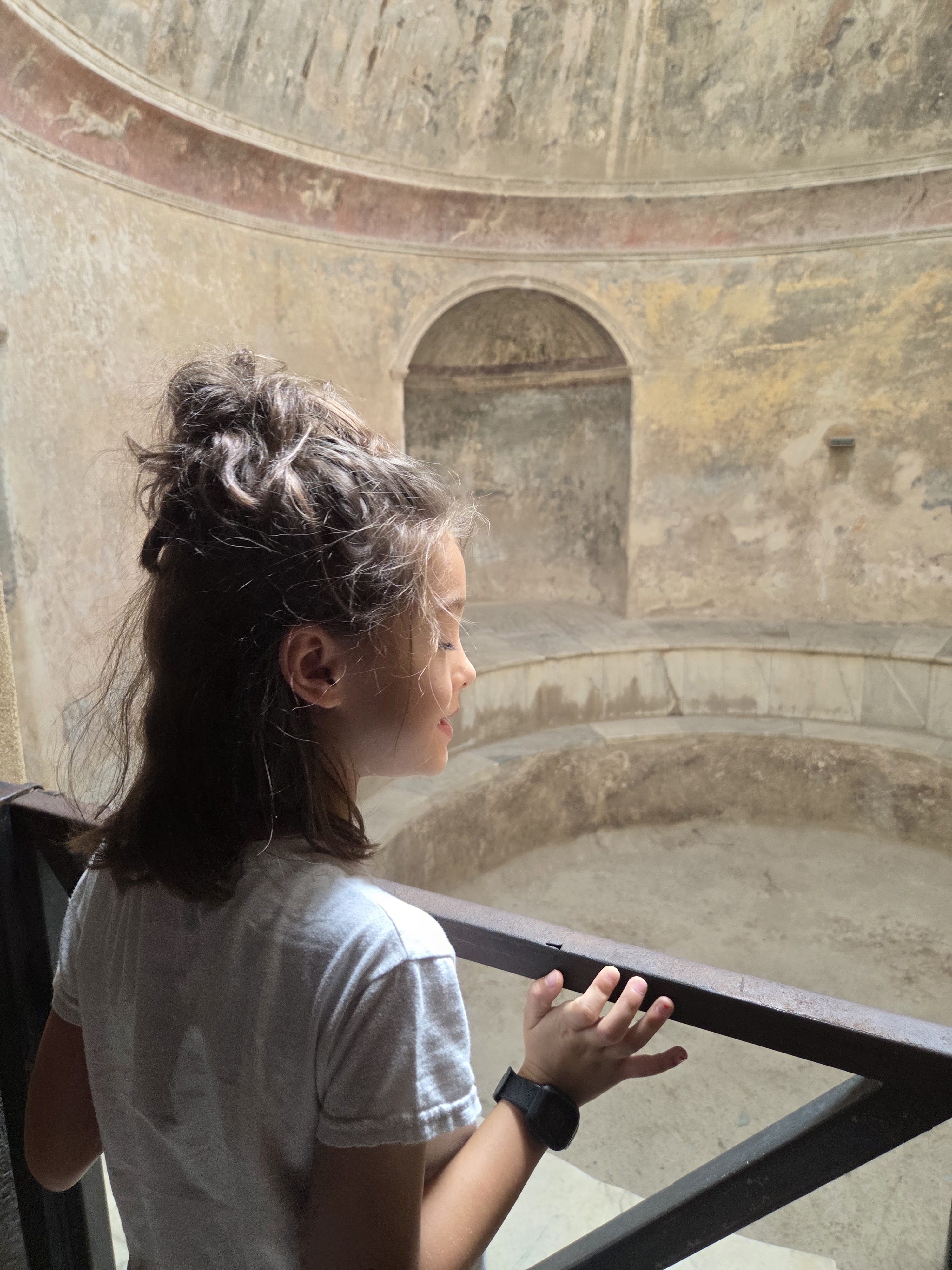 Remi looking into a round, domed bath chamber with a niche in the wall and a sunken pool