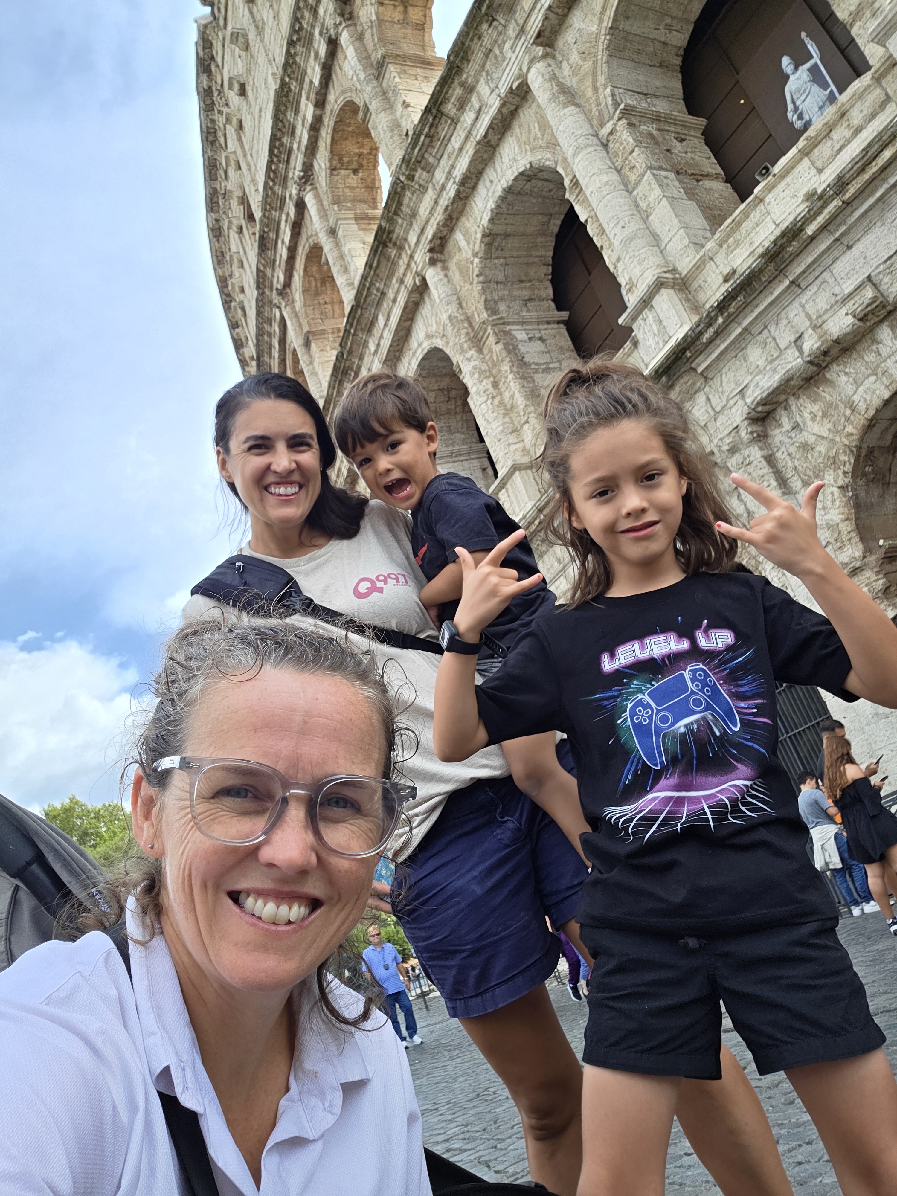 Alissa, Dani, Remi and Arlo in front of the Colosseum, Remi and Arlo both throwing rock-on hand signs