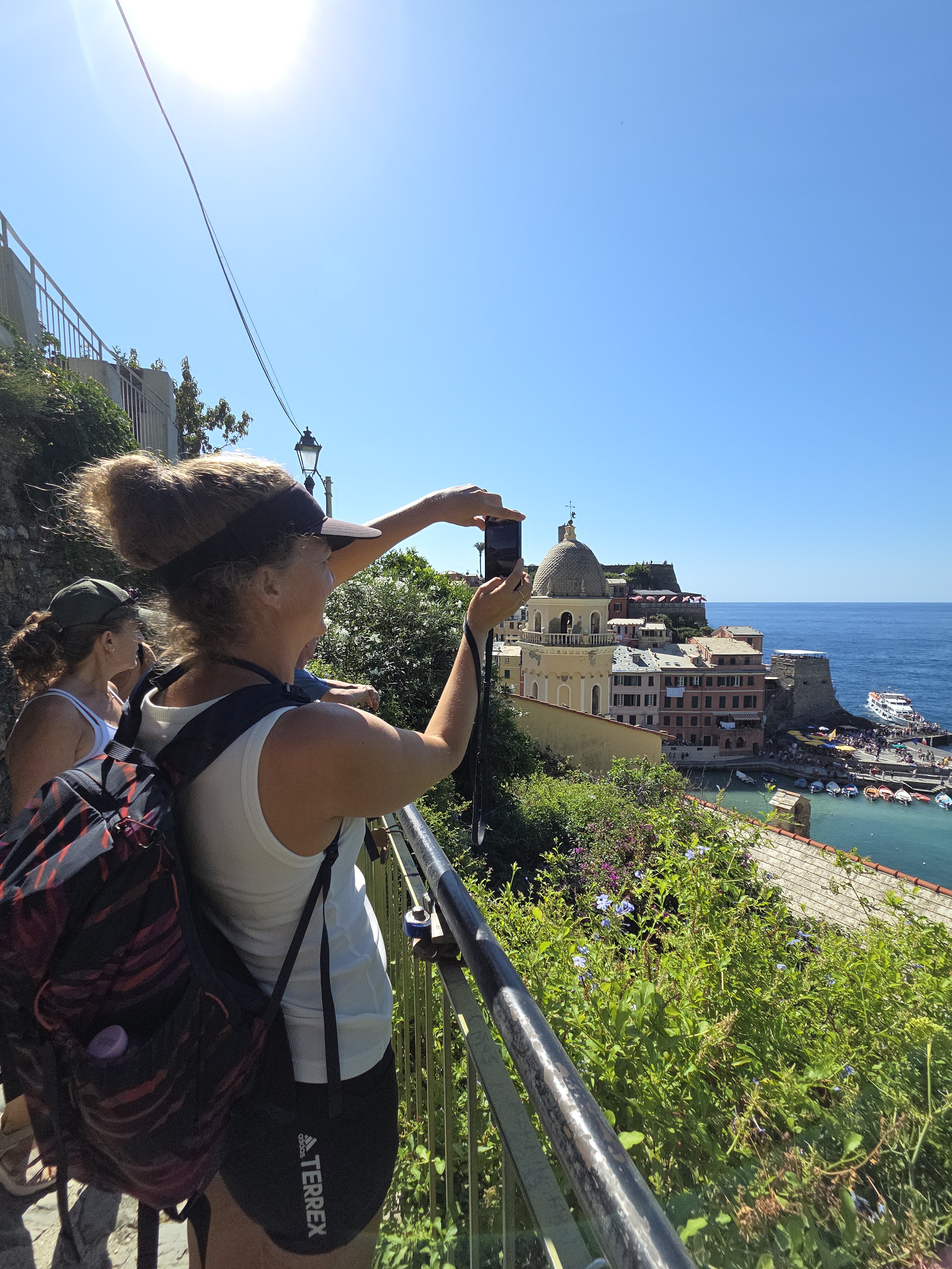 Mel photographing Vernazza's bell tower and harbor from a stone stairway overlook