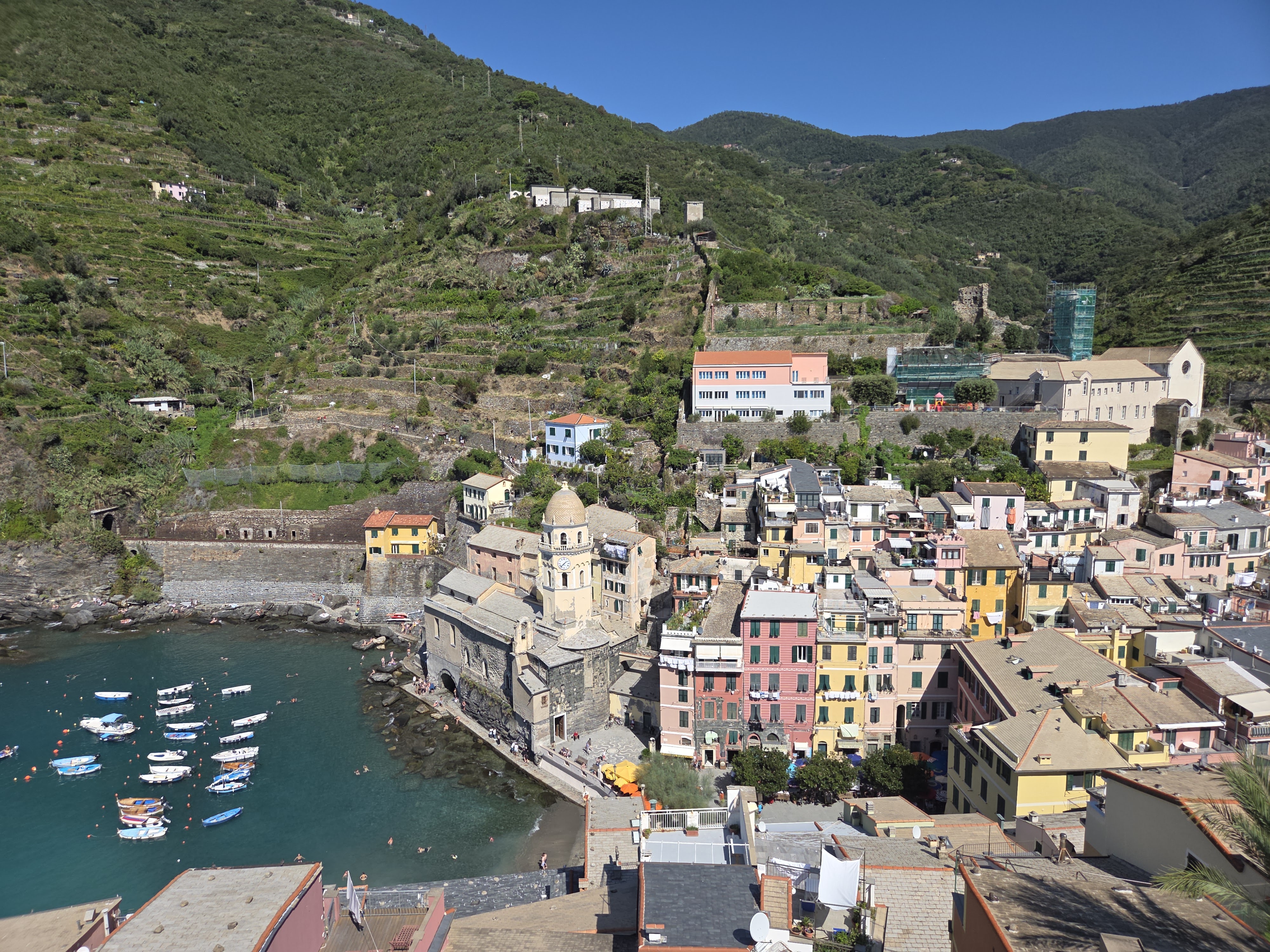 A panoramic view down over Vernazza's pastel buildings, church bell tower, and harbor from Castello Doria