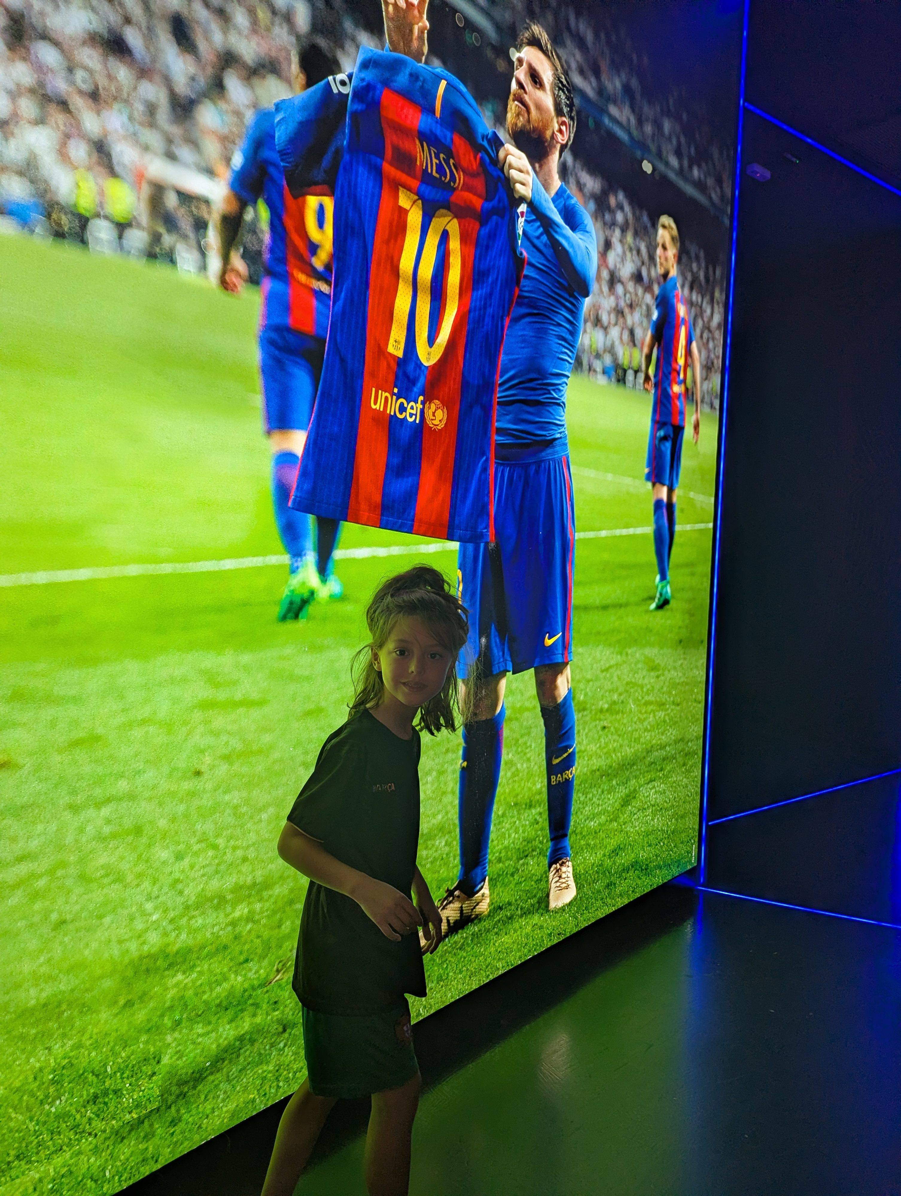 Remi standing in front of a giant screen showing Lionel Messi holding up a number 10 Barça jersey