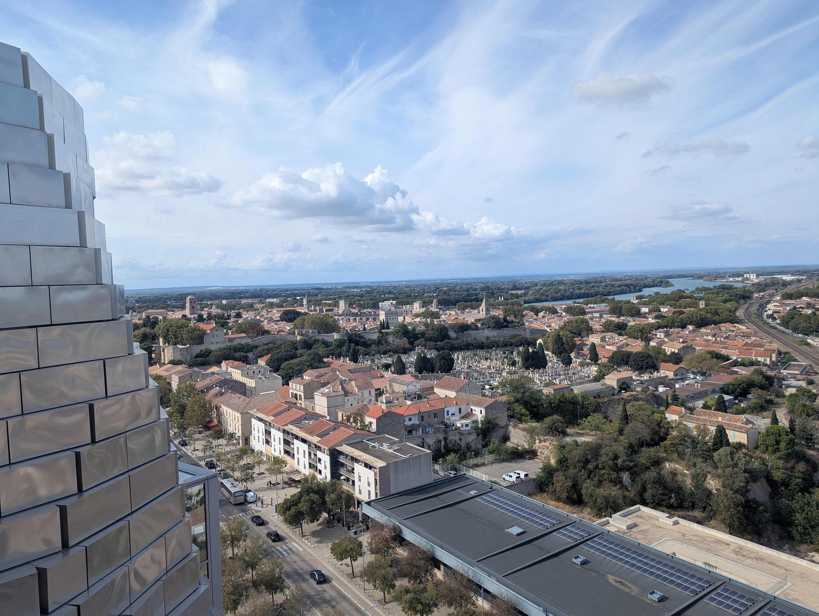 The view from the viewing platform of the LUMA tower over the red-tiled rooftops of Arles, the edge of the steel tower in the foreground and the Rhône in the distance