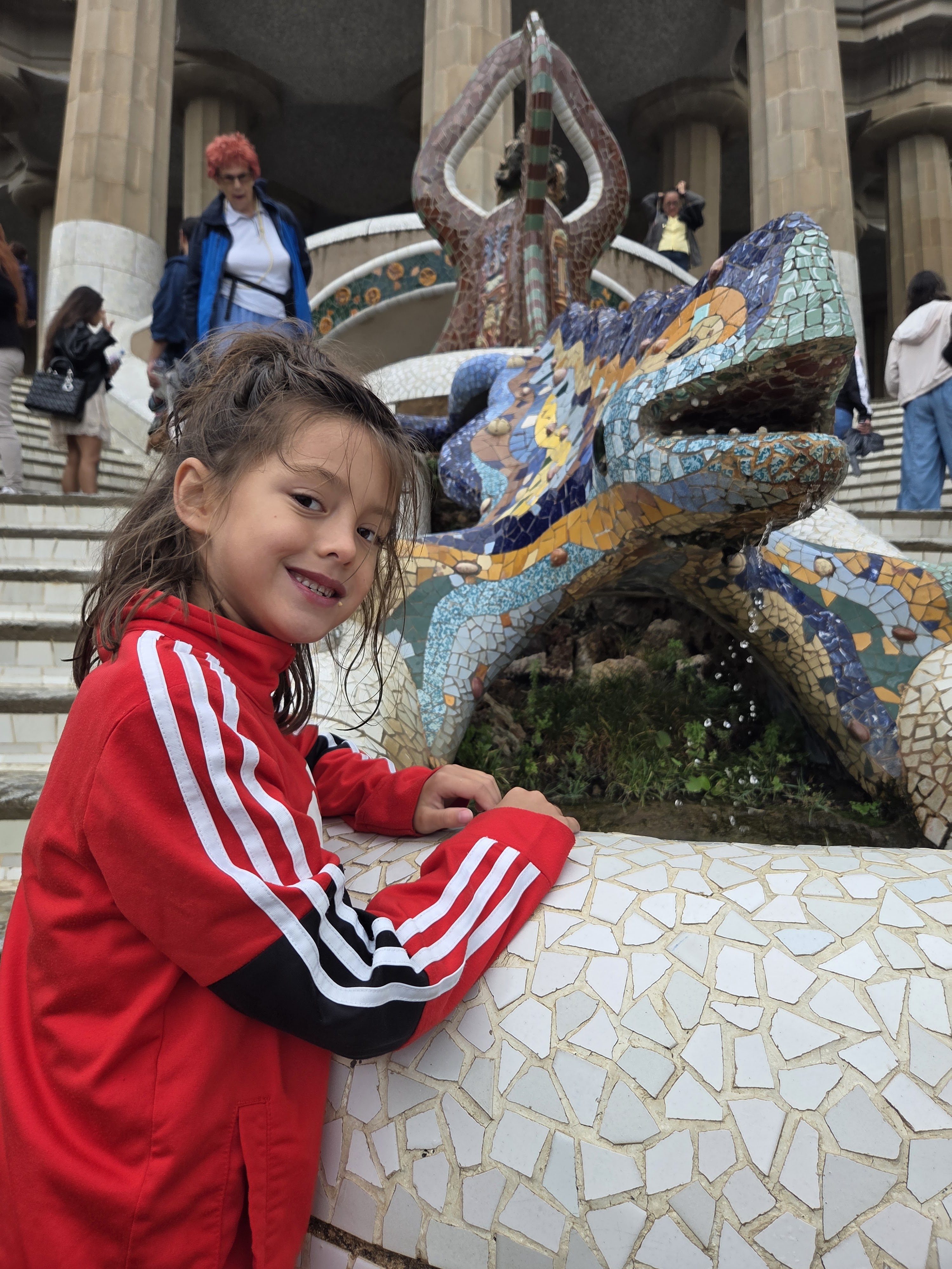 Remi smiling beside the mosaic dragon fountain in Parc Güell