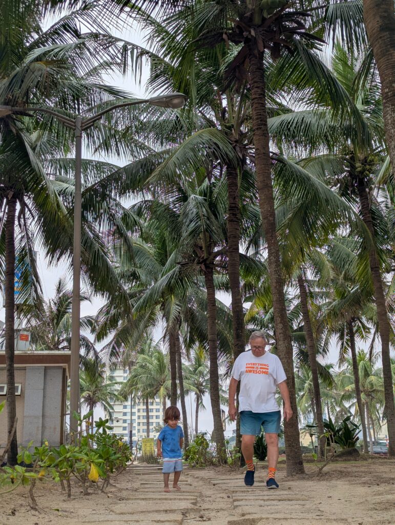 Toddler and grandpa walking to the beach in Da Nang Vietnam